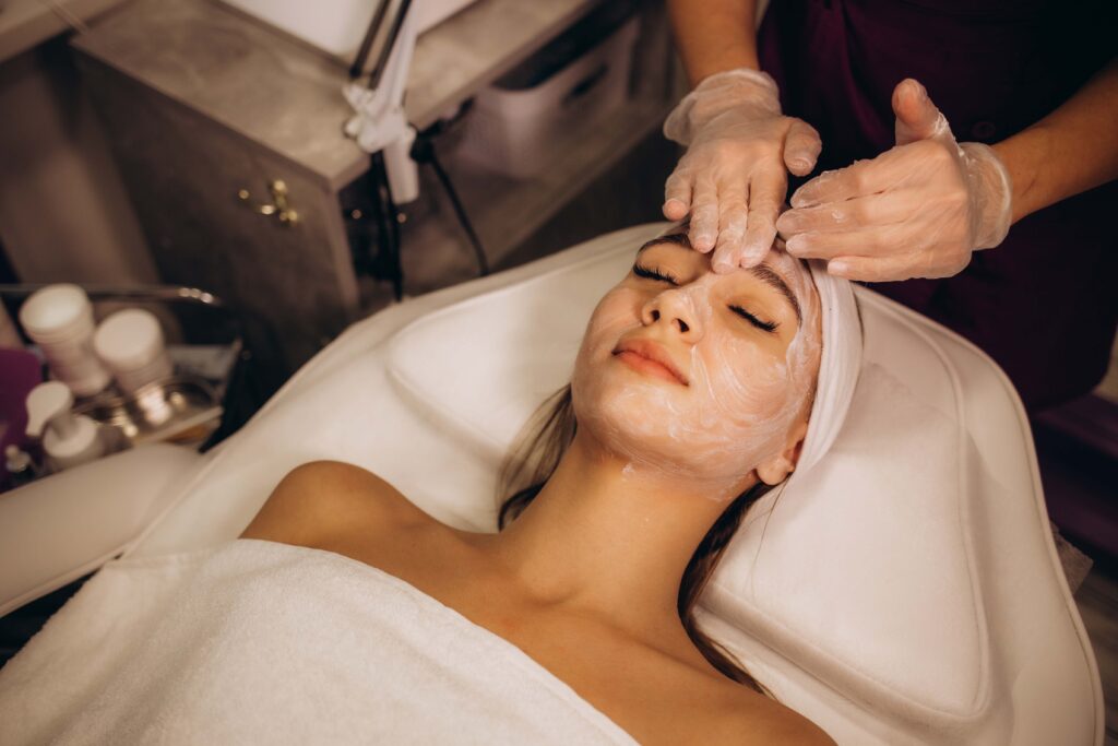 masseur doing facial massage to young woman on massage table on white background. Concept of massage spa treatments. Close-up